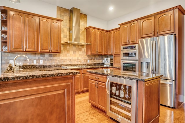 kitchen with light hardwood / wood-style flooring, stainless steel appliances, beverage cooler, tasteful backsplash, and wall chimney range hood