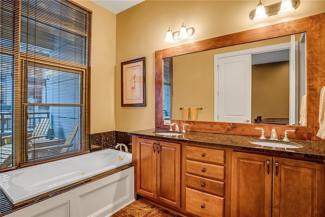 bathroom with vanity with extensive cabinet space, a bathtub, and double sink