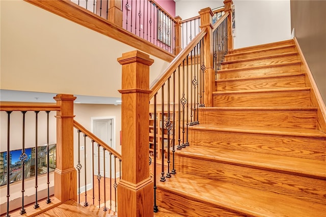 stairway with decorative columns and light wood-type flooring