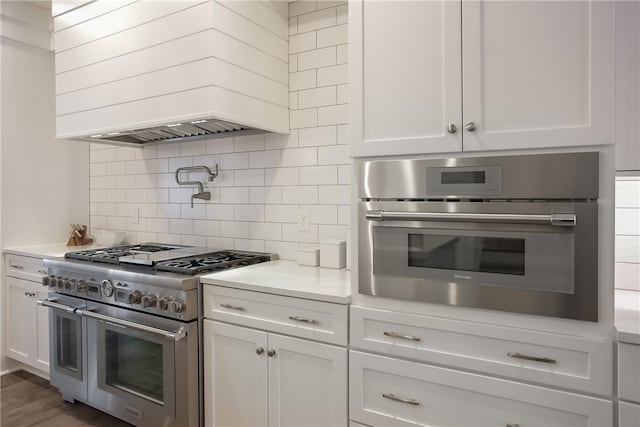 kitchen featuring appliances with stainless steel finishes, backsplash, custom exhaust hood, and white cabinets