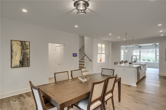 dining space with light wood-type flooring and sink