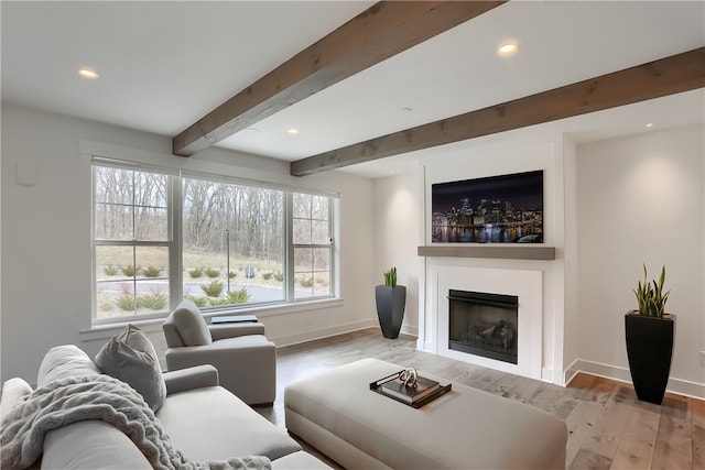 living room featuring light hardwood / wood-style floors, beamed ceiling, and a healthy amount of sunlight