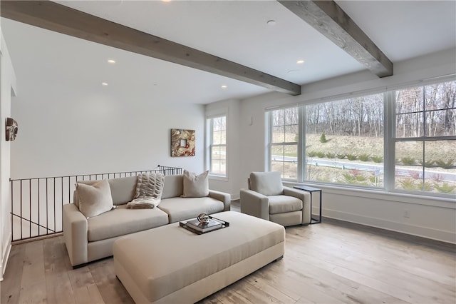 living room featuring light hardwood / wood-style flooring, a wealth of natural light, and beamed ceiling