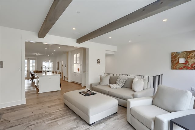 living room with beam ceiling, light hardwood / wood-style floors, and sink