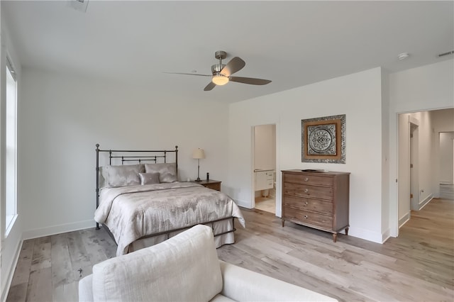 bedroom featuring ceiling fan, light hardwood / wood-style flooring, ensuite bathroom, and multiple windows