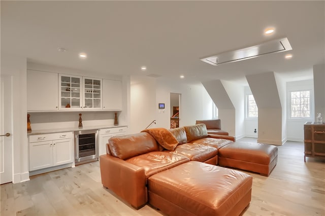 home theater room with bar, beverage cooler, and light hardwood / wood-style flooring