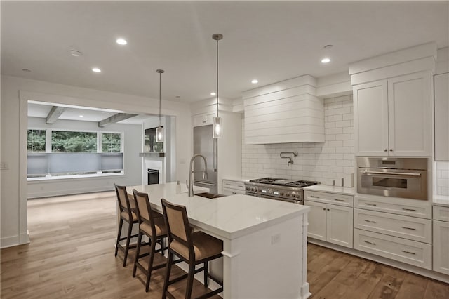 kitchen featuring appliances with stainless steel finishes, a center island with sink, sink, and wood-type flooring