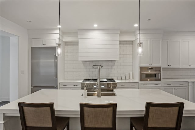 kitchen with white cabinets, a kitchen island with sink, high quality appliances, and tasteful backsplash