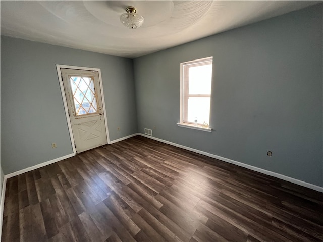 empty room with dark hardwood / wood-style flooring and a healthy amount of sunlight