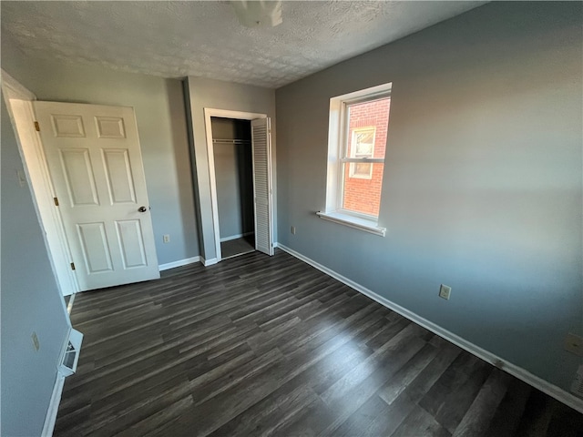 unfurnished bedroom with a closet, a textured ceiling, and dark hardwood / wood-style flooring