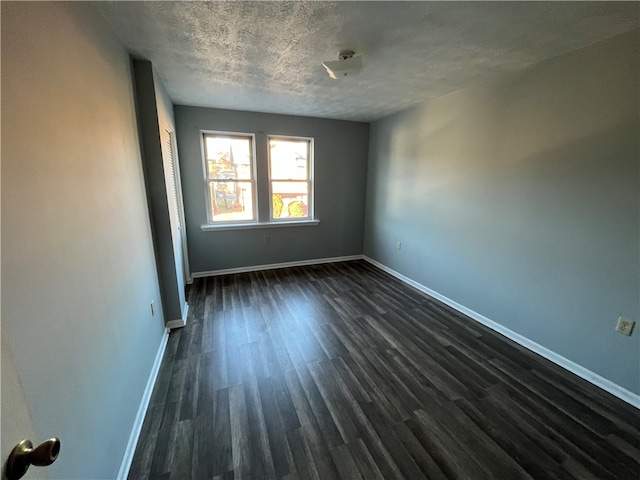 unfurnished room with dark hardwood / wood-style flooring and a textured ceiling