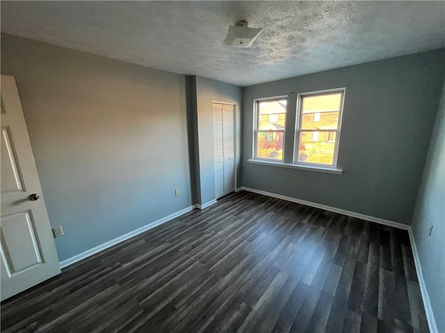 empty room with a textured ceiling and dark hardwood / wood-style floors