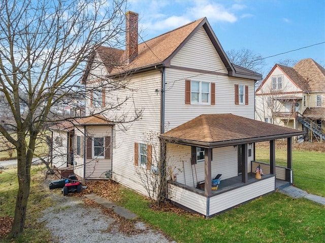 back of property with a lawn and a porch