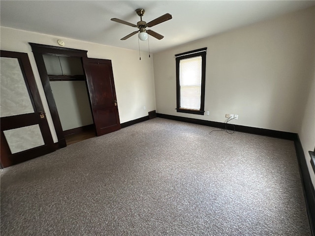 unfurnished bedroom with dark colored carpet, a closet, and ceiling fan