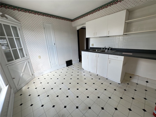 kitchen featuring tasteful backsplash, sink, and white cabinets