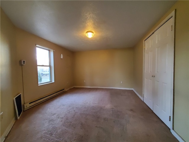 unfurnished bedroom featuring baseboard heating, carpet, a textured ceiling, and a closet