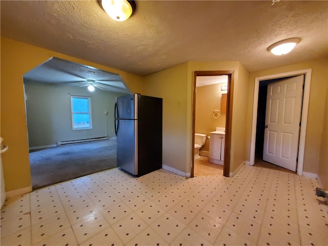 kitchen with a textured ceiling, baseboard heating, ceiling fan, and stainless steel refrigerator