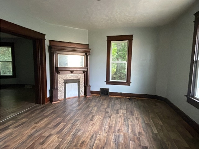 unfurnished living room with a textured ceiling and dark hardwood / wood-style flooring