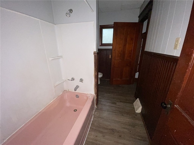 bathroom with toilet, wood-type flooring, and a washtub