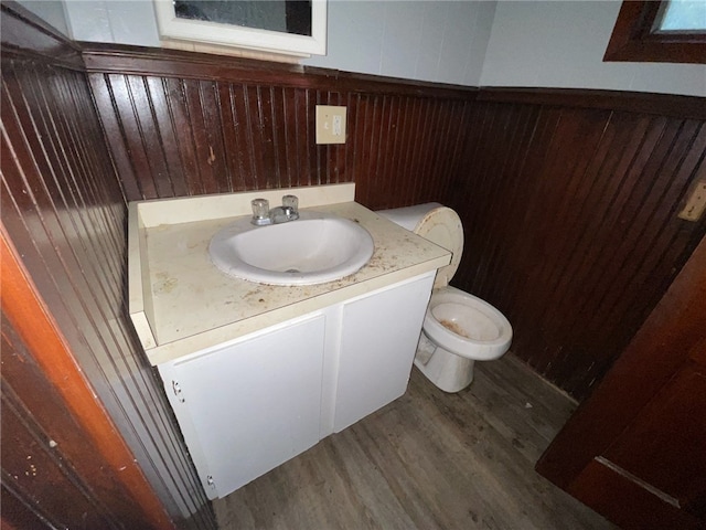 bathroom featuring vanity, wood walls, hardwood / wood-style floors, and toilet