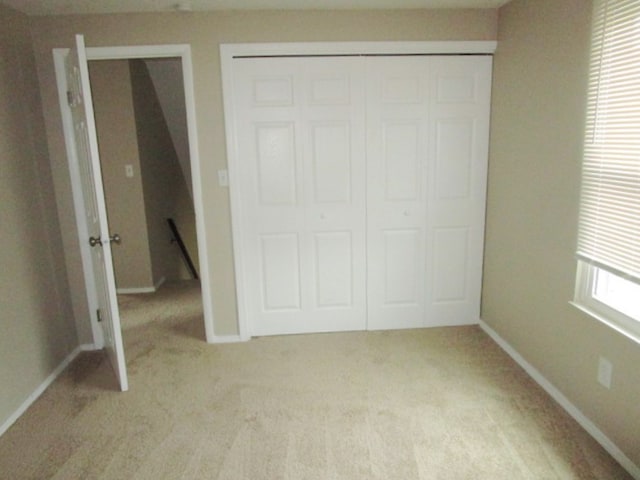 unfurnished bedroom with light colored carpet and a closet