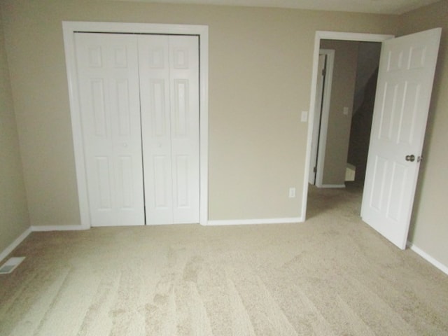 unfurnished bedroom featuring a closet and light colored carpet