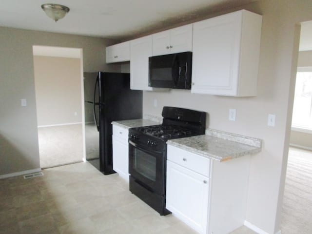 kitchen with black appliances, light stone countertops, and white cabinetry