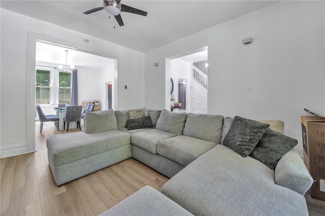 living room featuring ceiling fan with notable chandelier and light wood-type flooring