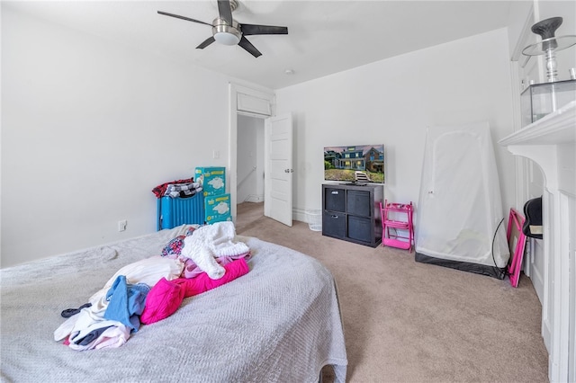 bedroom with light carpet, a fireplace, and ceiling fan