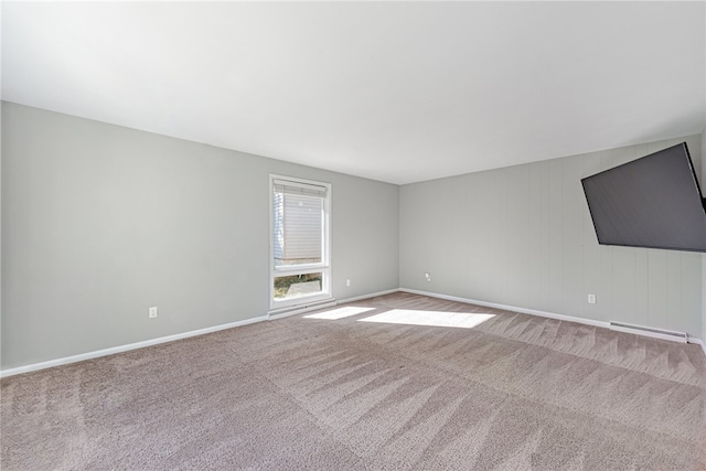 carpeted empty room featuring a baseboard heating unit