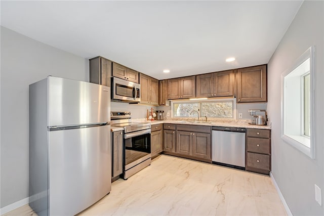 kitchen featuring stainless steel appliances, sink, and light stone countertops