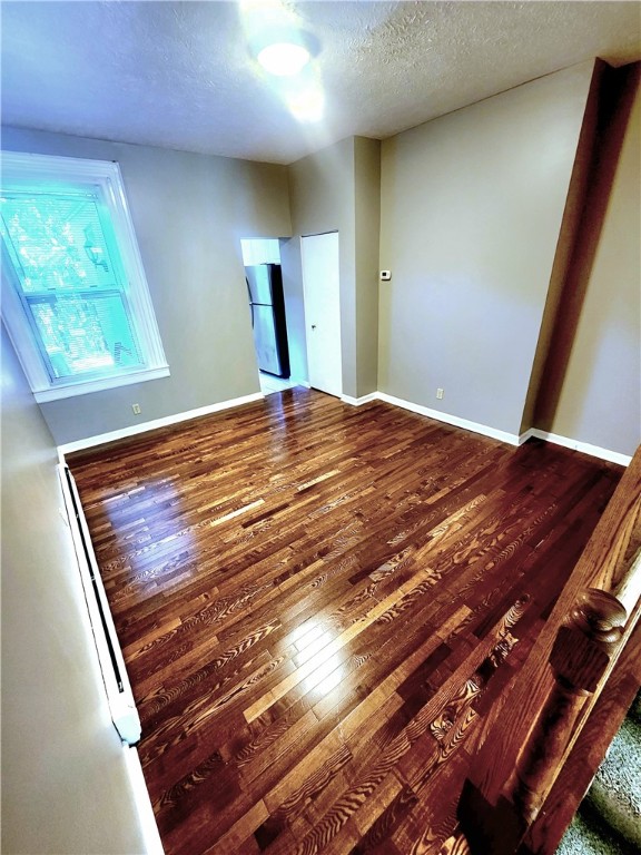 empty room with dark wood-type flooring and a textured ceiling