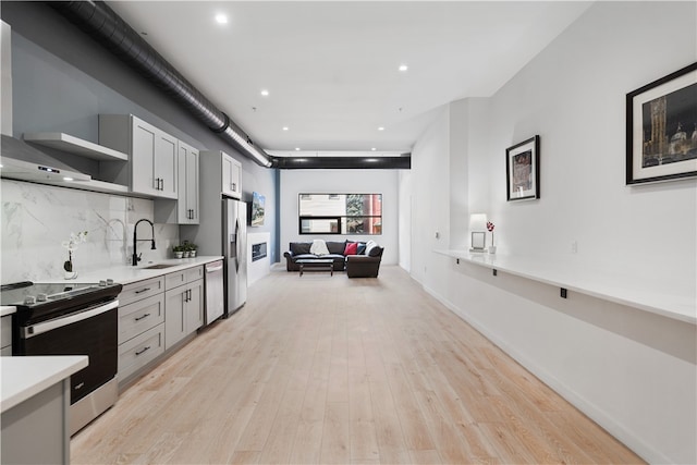 kitchen with light hardwood / wood-style flooring, sink, tasteful backsplash, and stainless steel appliances