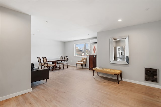 sitting room featuring a wall mounted AC and light wood-type flooring