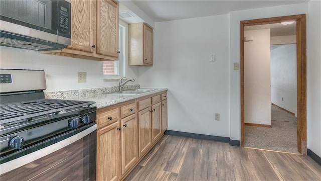 kitchen featuring stainless steel gas stove, dark wood-type flooring, sink, and light stone countertops