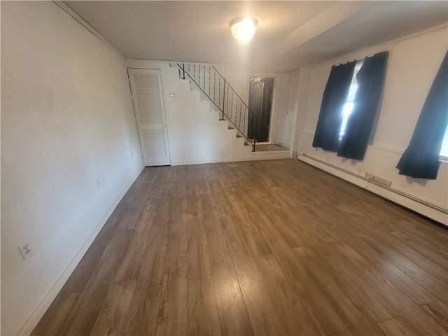 spare room featuring baseboard heating and dark hardwood / wood-style floors