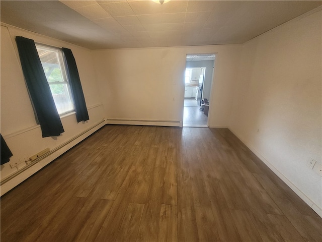 empty room with dark wood-type flooring and a baseboard heating unit