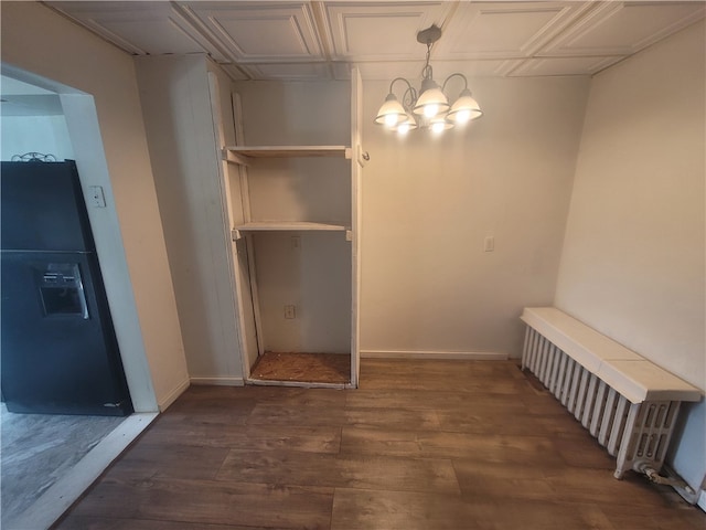 walk in closet with dark hardwood / wood-style flooring, a chandelier, and radiator