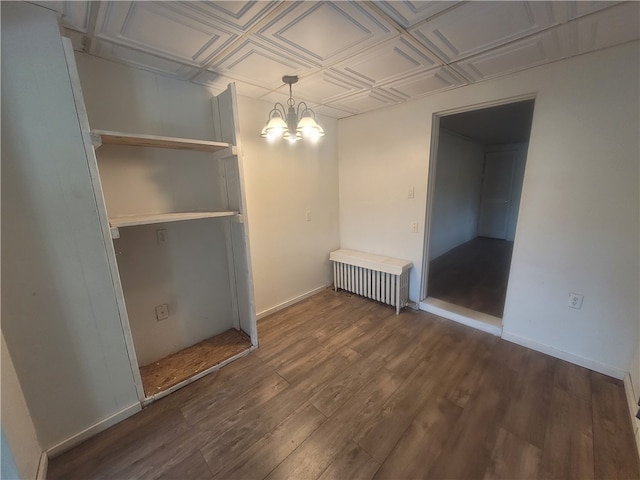 unfurnished bedroom featuring an inviting chandelier, dark wood-type flooring, and radiator