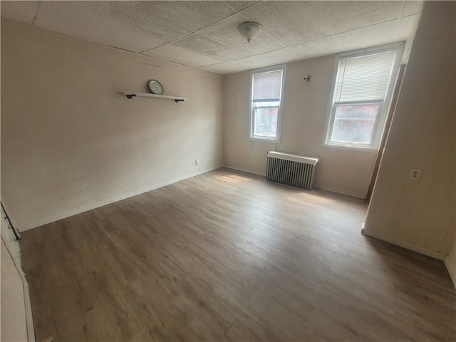 spare room featuring a paneled ceiling, radiator, and light wood-type flooring