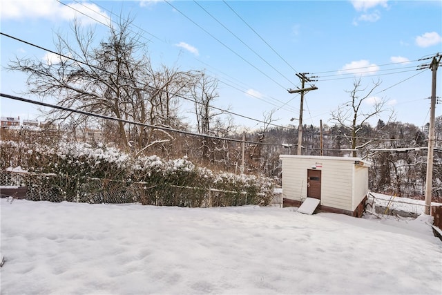 yard layered in snow featuring a storage unit