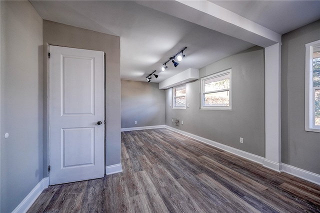 unfurnished room with rail lighting, dark wood-type flooring, and a wealth of natural light