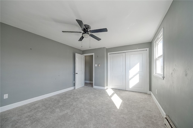 unfurnished bedroom featuring ceiling fan, a closet, light colored carpet, and a baseboard heating unit