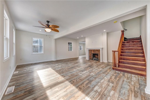 unfurnished living room featuring hardwood / wood-style floors, ceiling fan, and a brick fireplace