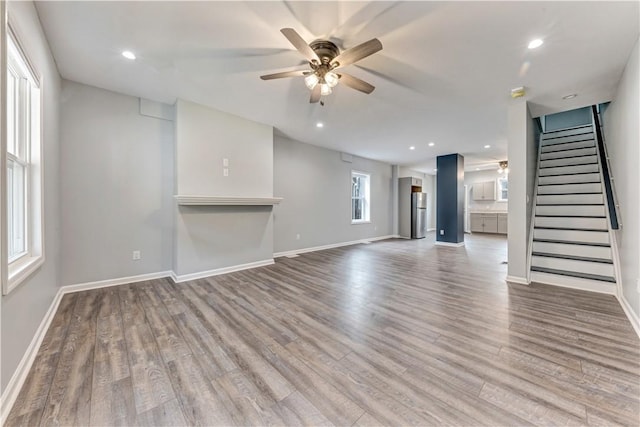 unfurnished living room featuring light wood-type flooring, plenty of natural light, and ceiling fan