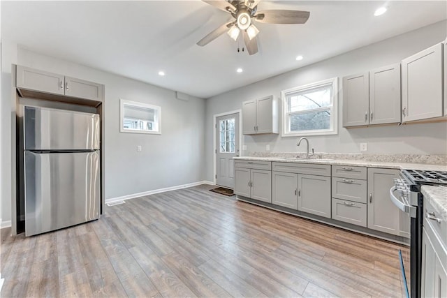 kitchen with gray cabinets, light hardwood / wood-style floors, and appliances with stainless steel finishes