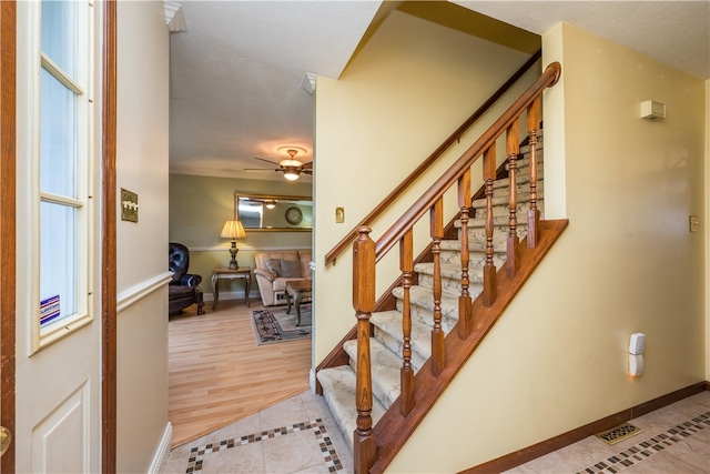 stairs featuring light hardwood / wood-style floors and ceiling fan