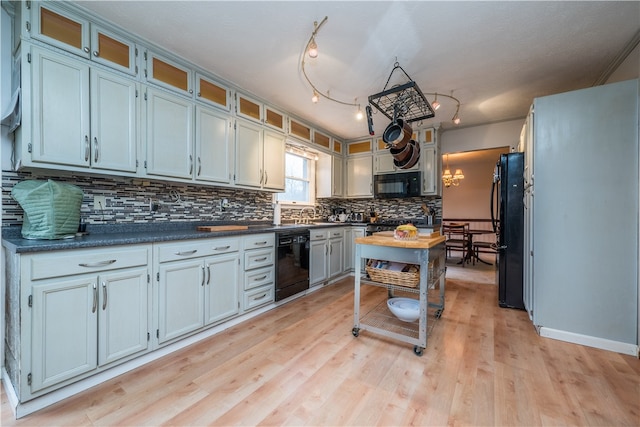 kitchen featuring tasteful backsplash, white cabinetry, track lighting, light wood-type flooring, and black appliances