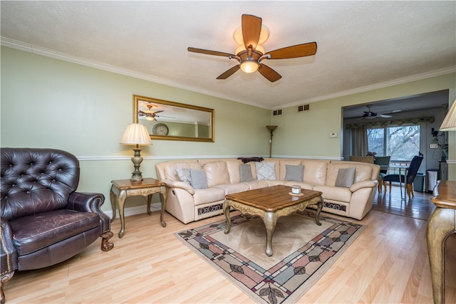 living room featuring ceiling fan, light wood-type flooring, and crown molding