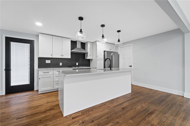 kitchen with tasteful backsplash, dark hardwood / wood-style flooring, white cabinets, wall chimney exhaust hood, and stainless steel refrigerator